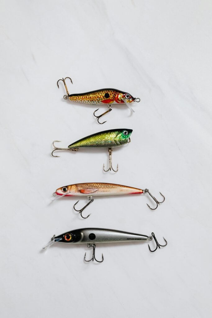 Flat lay of four vibrant fishing lures on a light background, displaying varied designs.